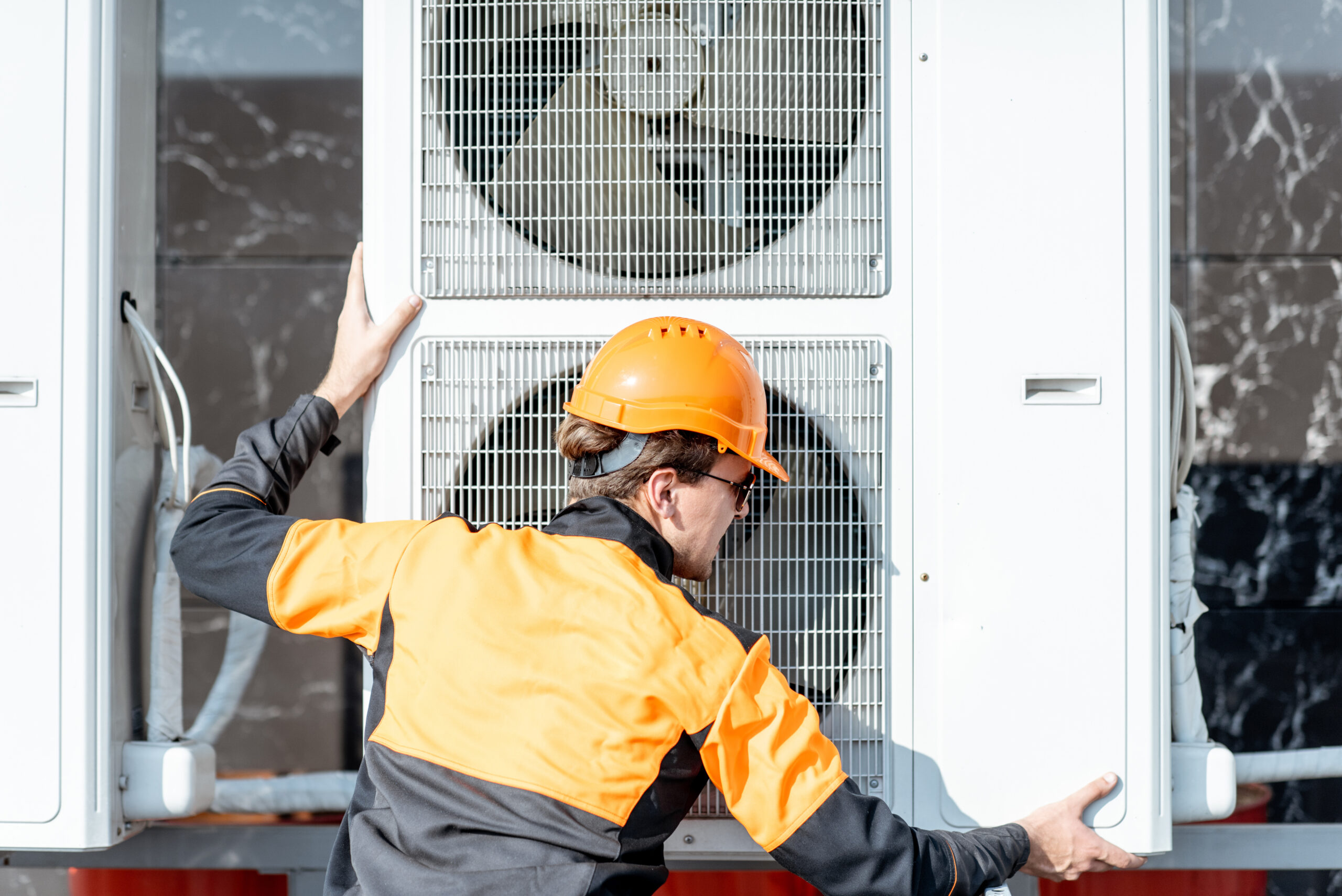 Workman installing outdoor unit of the air conditioner